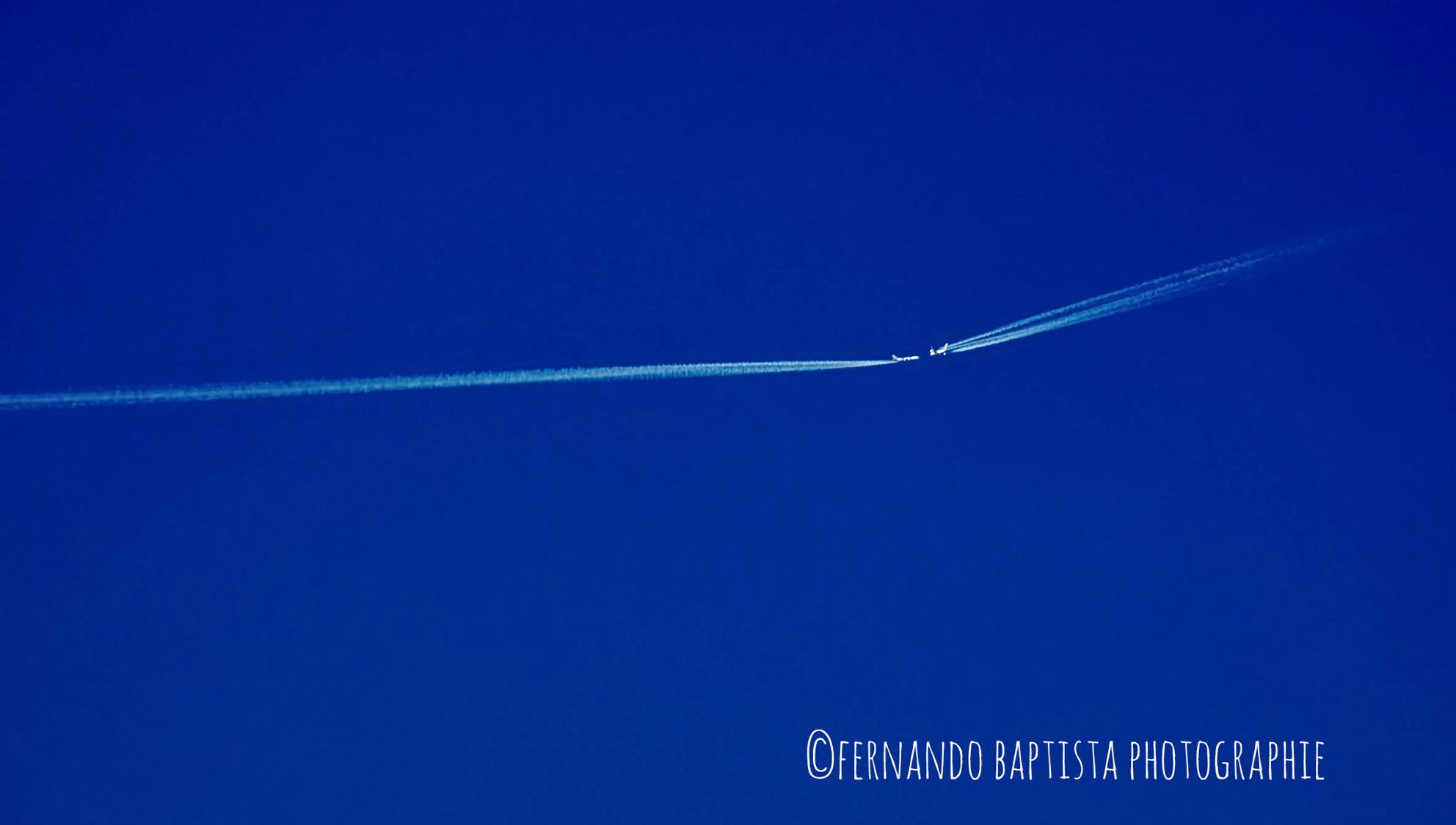 Zwei Flugzeuge am wolkenlosen, blauen Himmel, die vermeintlich aufeinenader zufliegen